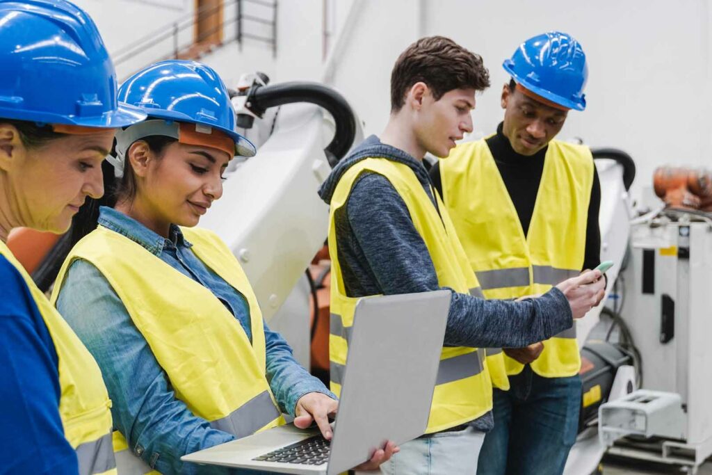 Multiracial industrial engineers working at automated AI robotic production factory - New technology concept